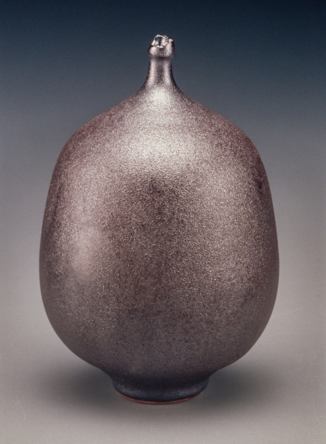 A rounded vase with a short skinny neck and a textured, red-black glaze.