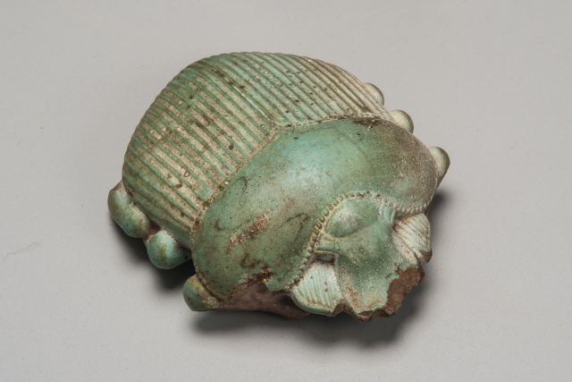 A light green glazed scarab that is fully three-dimensional with carefully defined features: head, legs, and wings. It is chipped at edges.